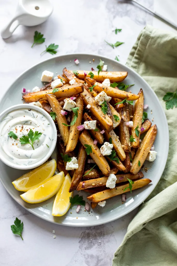 Golden crispy Greek fries topped with crumbled feta, fresh parsley, and red onion