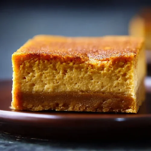 Keto pumpkin cheesecake bar on its side showing the almond crust and pumpkin layer