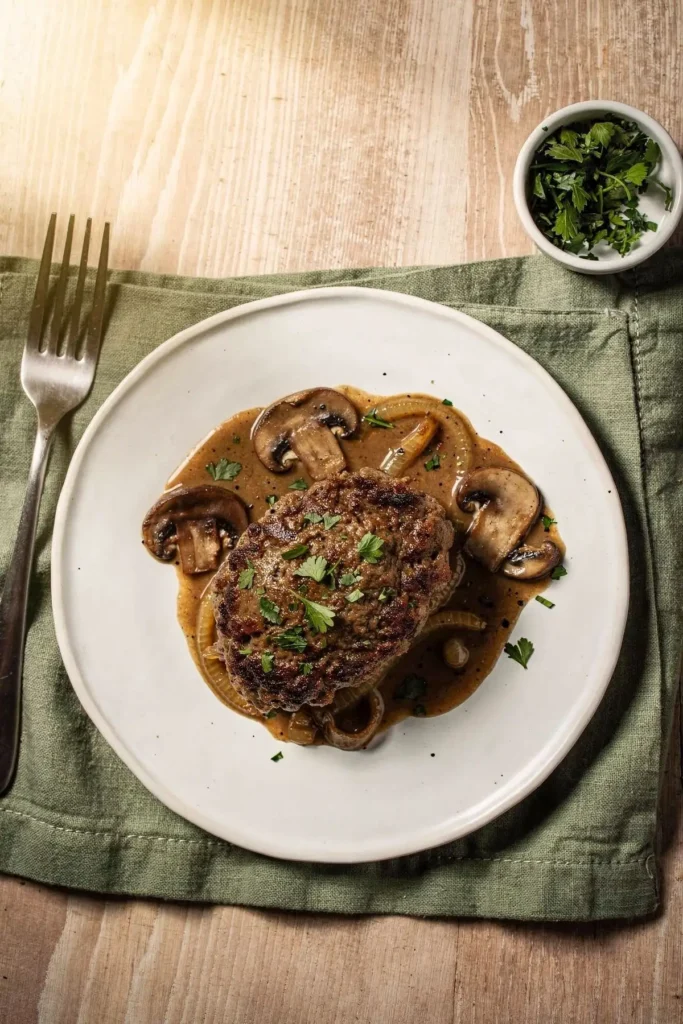 Salisbury steak with onion mushroom gravy on a white plate, seen from above